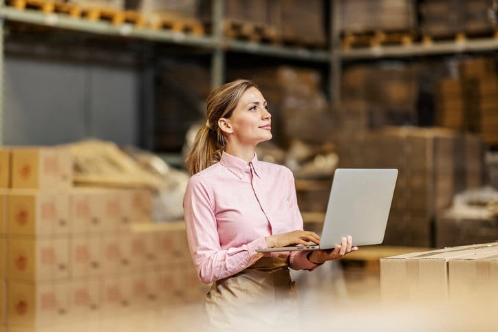 woman working in food manufaturing warehouse on laptop